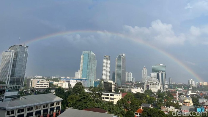 Pelangi muncul di kawasan Pancoran, Jakarta Selatan, Selasa (3/2/2026), setelah hujan reda. Momen langka ini menarik perhatian para pekerja kantoran.