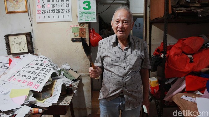 Akwet berpose dengan kuas kaligrafi ukuran besar. Ia menjelaskan, terputusnya keahlian menulis kaligrafi China secara manual karena faktor politik (larangan budaya China tahun 60an) hingga pengaruh teknologi (banyak yang memesan dalam bentuk grafis digital).