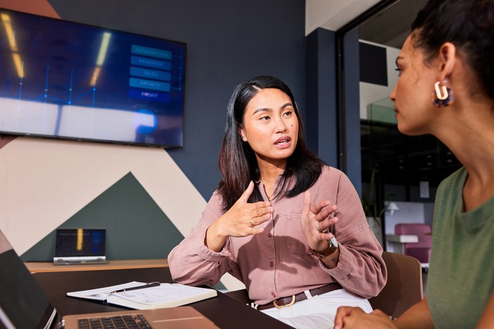 Multi racial mid adult female co-workers in their 30s having serious discussion, planning, strategy, problem solving