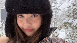 Dia memakai topi berbulu dan membiarkan rambut panjangnya tergerai menutupi bagian dada serta bikini topnya, kemudian dipadankan dengan setelan pakaian hangat berupa puffer jacket dan sweatpants dari NOCTA, sub-brand Nike. Foto: dok. Instagram @lalalalisa_m