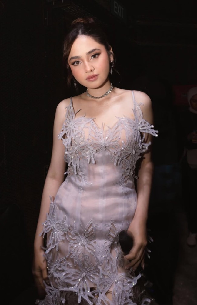 Penampilan Syifa itu diunggah oleh desainer dress yang dikenakannya, KRINOU. Gaun mini berwarna nude dan abu-abu keperakan itu memiliki potongan sleeveless dengan tali tipis. Silhouette fitted yang mengikuti bentuk tubuh memberikan kesan ramping. Foto: Instagram/@krinouofficial