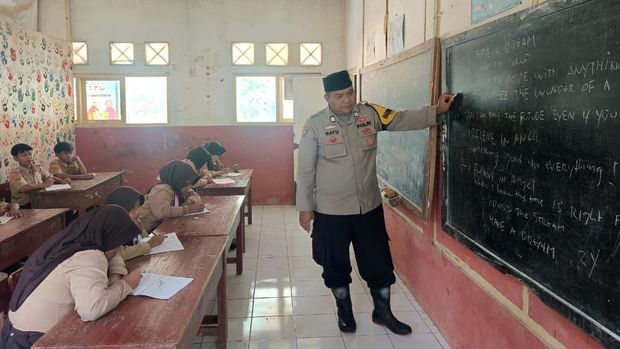 Bhabinkamtibmas Polsek Mande, Polres Cianjur, Bripka Bayu Angga Kusumanegara mengajar Bahasa Inggris kepada siswa Madrasah Ibtidaiyah (MI) Al Jihad.