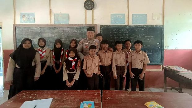 Bhabinkamtibmas Polsek Mande, Polres Cianjur, Bripka Bayu Angga Kusumanegara mengajar Bahasa Inggris kepada siswa Madrasah Ibtidaiyah (MI) Al Jihad.