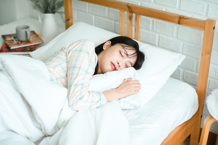 Asian woman sleeping, high angle view of beautiful young woman lying in bed and keeping eyes closed