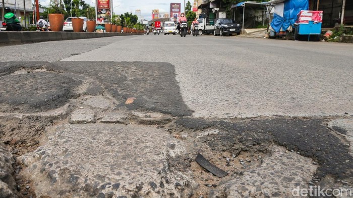 Pengendara melintas di Jalan Siliwangi Raya, Pamulang, Tangerang Selatan, Banten, Jumat (6/2/2026). Kondisi jalan berlubang berpotensi memicu kecelakaan lalu lintas jika pengendara tidak berhati-hati.
