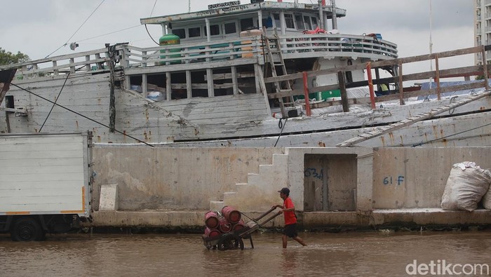 Para pekerja tetap beraktivitas di tengah banjir rob yang menggenangi kawasan Pelabuhan Sunda Kelapa, Jakarta Utara, Jumat (6/2/2025).