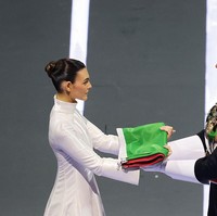 Ceretti menyerahkan bendera Italia kepada penjaga kehormatan Carabinieri, Corazzieri, setelah tampil mengenakan setelan putih, merah, dan hijau yang merepresentasikan warna bendera negaranya. Foto: Getty Images/Elsa