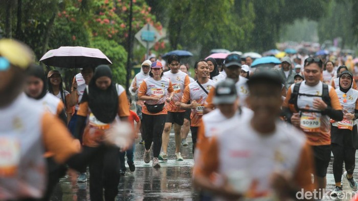 Hujan mengiringi aktivitas warga di Taman Mini Indonesia Indah (TMII), Jakarta. Meski cuaca basah, TMII tetap ramai oleh warga yang berlari.