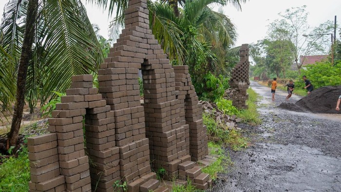 Sejumlah anak-anak bermain di area candi paving di Desa Sembulungan, Cluring, Banyuwangi, Jawa Timur, Minggu (8/2/2026). Sebanyak 13 bangunan menyerupai candi yang terbuat dari bahan paving material proyek pembangunan jalan yang tak kunjung dikerjakan itu dibangun warga menjadi karya seni dan bentuk protes karena menyebabkan penyempitan dan mengganggu pengguna jalan. ANTARA FOTO/Budi Candra Setya