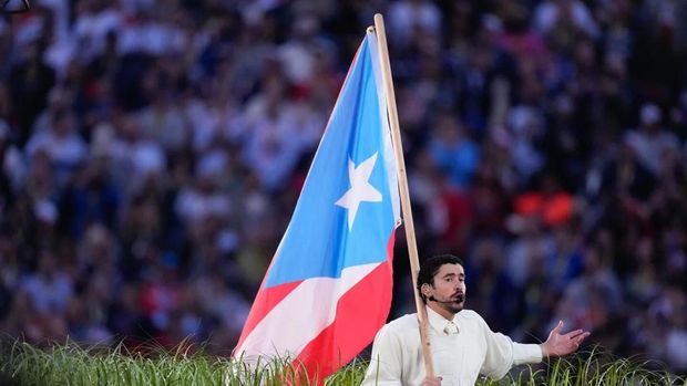 Bad Bunny membawa bendera Puerto Rico, tempat kelahirannya, saat tampil dalam Super Bowl Halftime Show di California pada Minggu (8/2). (AP Photo/Mark J. Terrill)