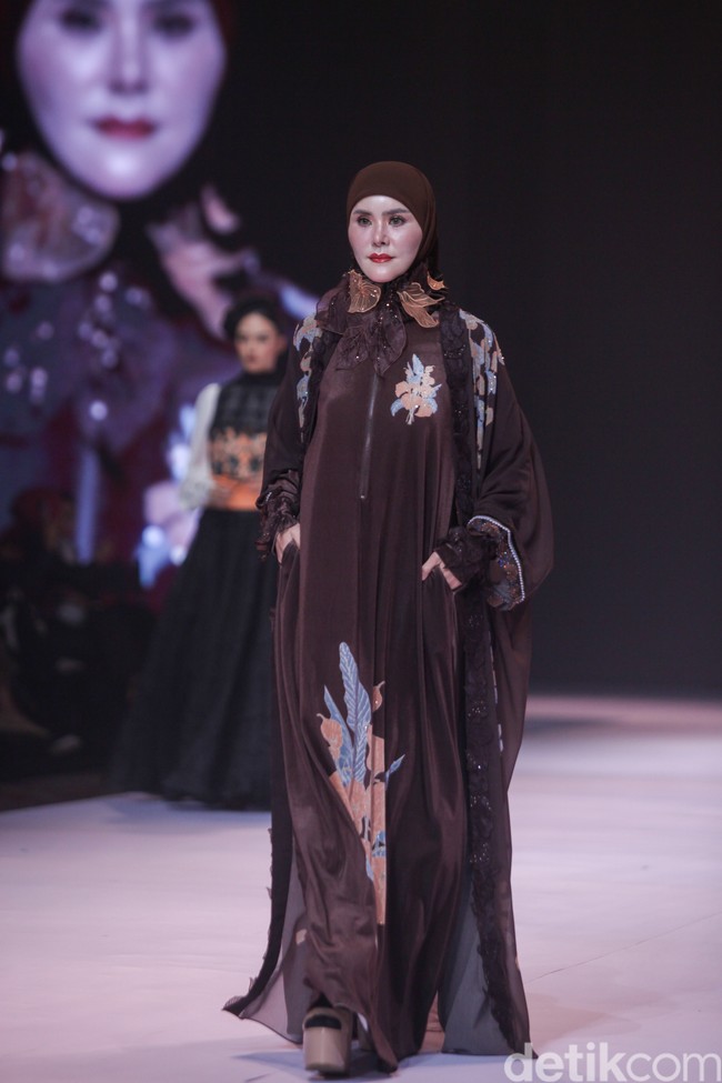 Angel Lelga mengenakan busana karya Lia Soraya, yang menonjolkan perpaduan bahan satin cokelat tua dengan aksen bordir floral yang artistik. Foto: Gilang Faturahman/detikFoto.