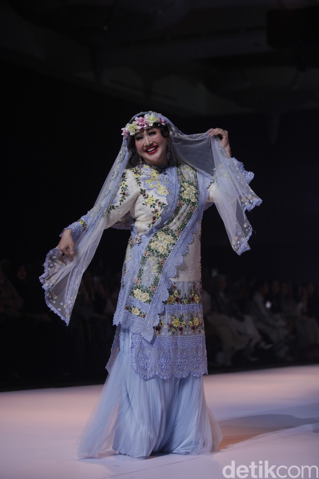 Selain istri pejabat, ada juga deretan selebriti yang menjadi model runaway. Salah satunya aktris senior, Paramitha Rusady tampil dalam balutan busana Mazulabel milik Marini Zumarnis, yang memadukan nuansa feminin dan elegan, lengkap dengan aksen bunga serta kerudung transparan yang memperkuat aura anggunnya di atas panggung. Foto: Gilang Faturahman/detikFoto.