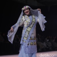 Selain istri pejabat, ada juga deretan selebriti yang menjadi model runaway. Salah satunya aktris senior, Paramitha Rusady tampil dalam balutan busana Mazulabel milik Marini Zumarnis, yang memadukan nuansa feminin dan elegan, lengkap dengan aksen bunga serta kerudung transparan yang memperkuat aura anggunnya di atas panggung. Foto: Gilang Faturahman/detikFoto.