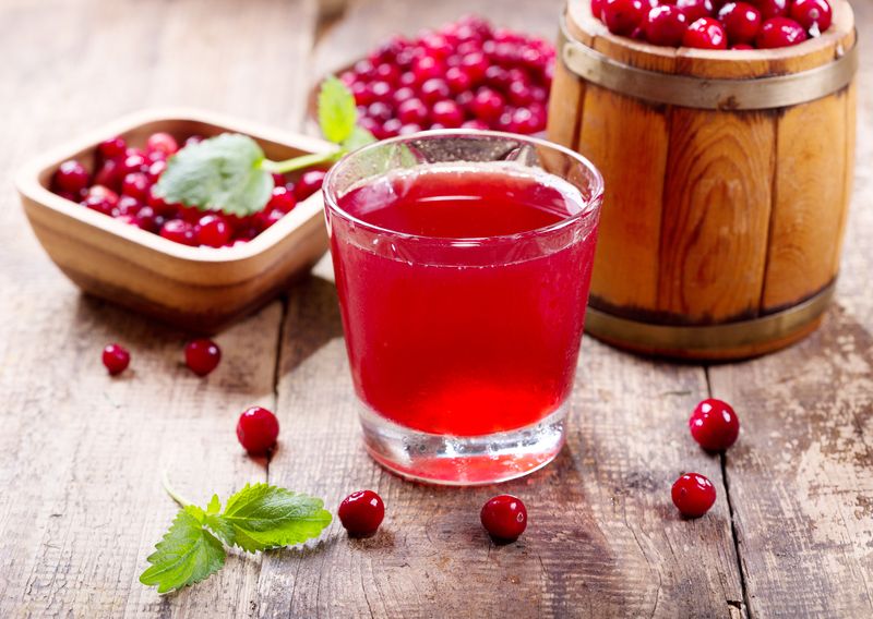 glass of cranberry juice with fresh berries on wooden table