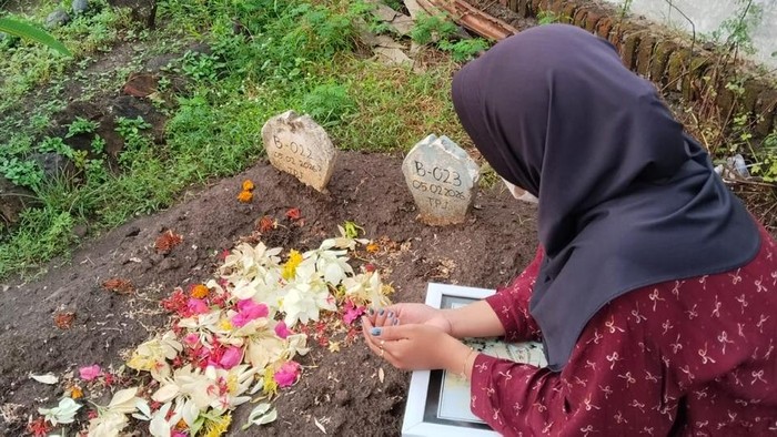 Nadia Putri Rahmawati saat mengunjungi pusara pemakaman masal yang ia duga sebagai jenazah suaminya Deni Purwanto.