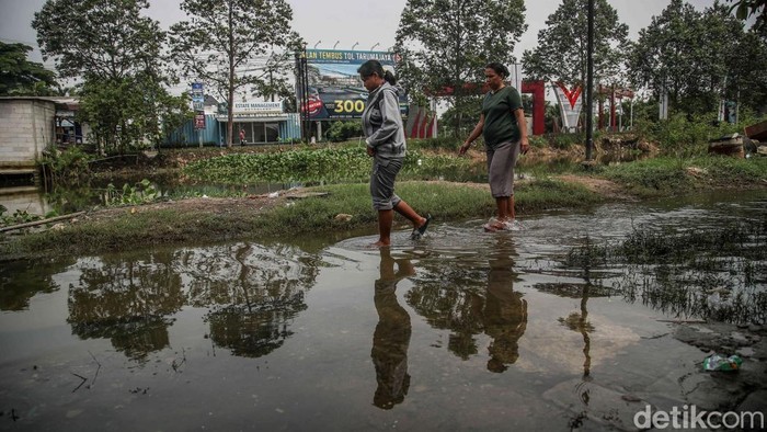 Sejumlah warga beraktivitas di Desa Buni Bakti, Kabupaten Bekasi, Jawa Barat, Kamis (12/2/2026), setelah banjir berangsur surut. Air sempat naik cepat akibat luapan Kali CBL yang dipicu banjir kiriman dari Bogor, membuat warga kembali waswas.