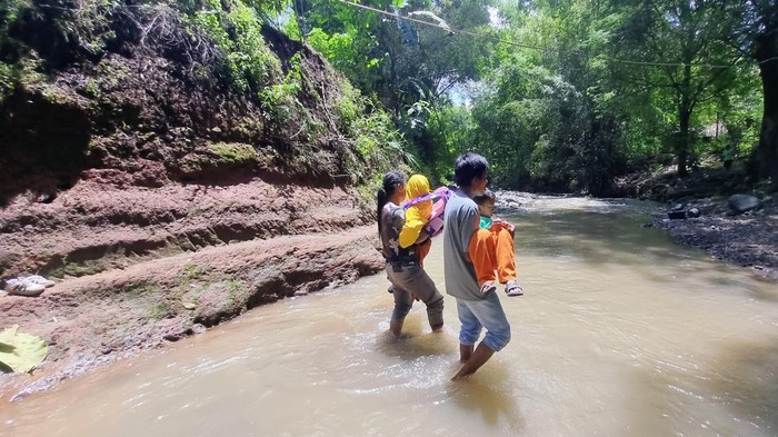 Warga di Dusun Karangsengon, Desa Sidoharjo, Ponorogo melintasi sungai karena jembatan rusak setelah diterjang banjir