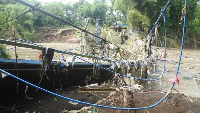 Warga mengamati jembatan gantung Darus atau Jembatan Cinta yang terputus akibat banjir di Desa Jubung, Sukorambi, Jember, Jawa Timur, Sabtu (14/2/2026). Jembatan penghubung Kecamatan Sukorambi dan Ajung tersebut terputus akibat banjir pada Kamis (12/2) yang mengakibatkan warga harus menggunakan rute lain sejauh tujuh kilometer dari sebelumnya satu kilometer. ANTARA FOTO/Seno.