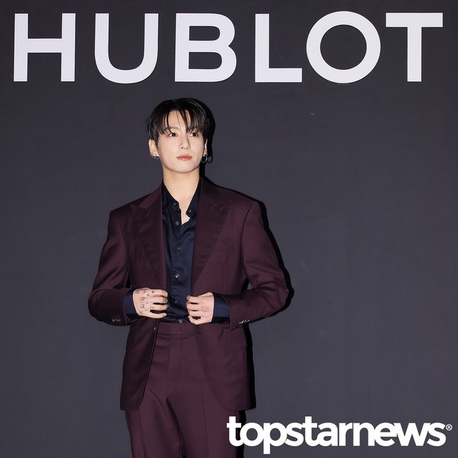 Dalam kesempatan itu, Jungkook BTS memancarkan pesonanya memakai kemeja hitam berbalut setelan jas berwarna burgundy wine. Sejumlah tindik telinganya menambah kesan edgy. Foto: Instagram