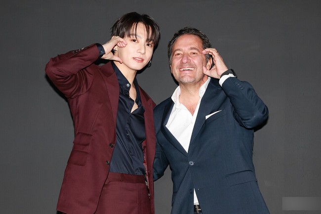 Interaksi Jungkook BTS dengan CEO Hublot juga membuat penggemar gemas. Lantaran Jungkook mengajarinya berpose membuat heart sign di pipi. Foto: Instagram