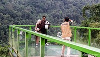 Pasangan wisatawan terlihat berfoto di area Sky Walk yang menawarkan pemandangan alam terbuka dari ketinggian.