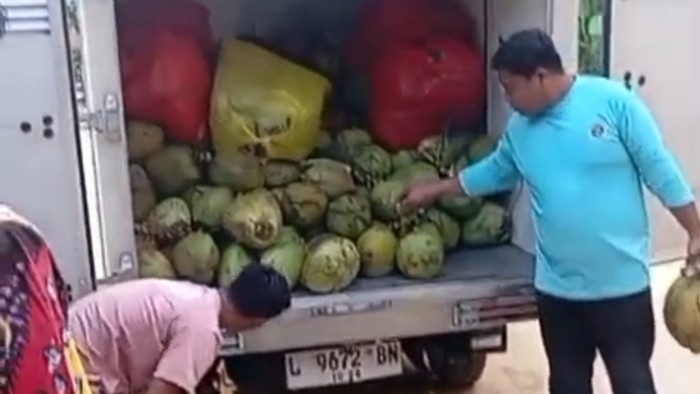 Petugas SPPG di Kec. Palengan, Pamekasan menurunkan kelapa muda dan telur mentah untuk dibagikan ke siswa