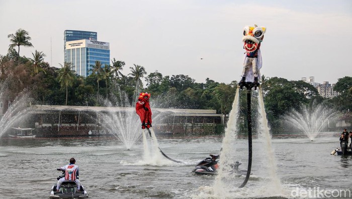 Atraksi barongsai di atas air memukau pengunjung Senayan Park saat long weekend Imlek 2577. Pertunjukan Aerial Lion Dance jadi tontonan unik di tepi danau.