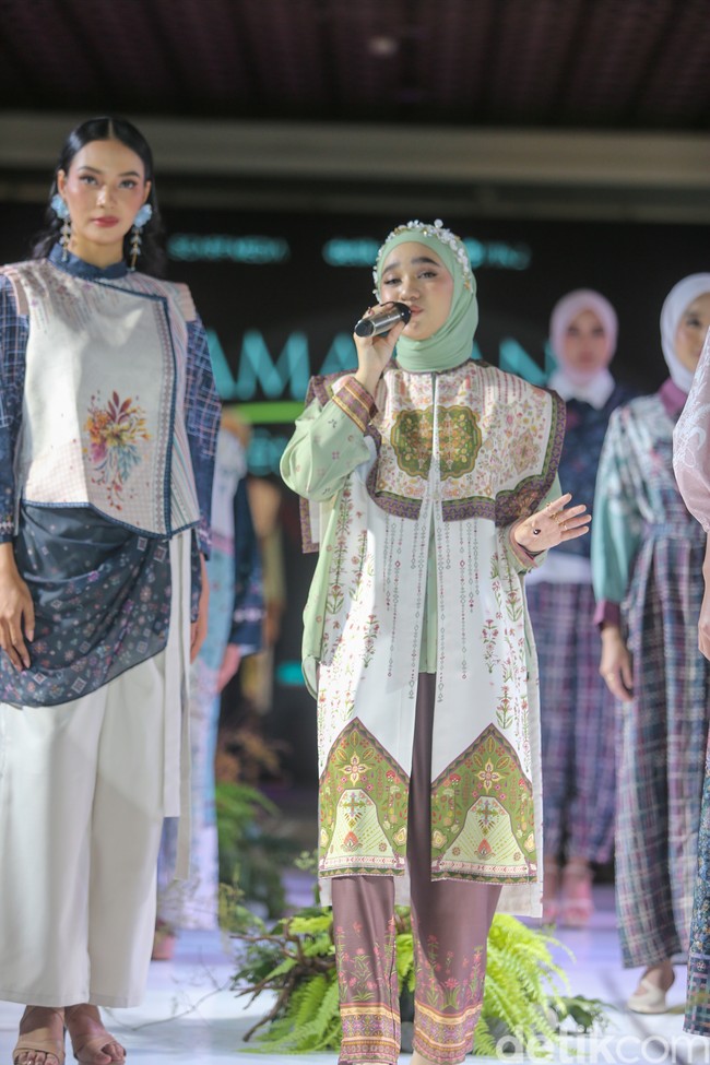 Keseluruhan look ini disempurnakan dengan celana panjang longgar berwarna cokelat tua yang memiliki detail motif etnik di bagian bawah, menciptakan keselarasan gaya yang elegan. Foto: Andhika Prasetia/detikFoto.