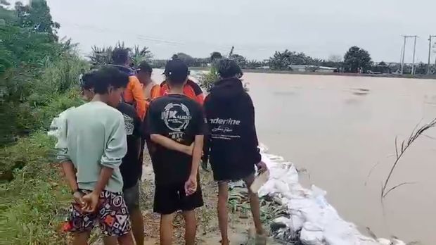 Petugas gabungan memantau tanggul sungai yang diperkuat menggunakan kantong berisi pasir di Desa Gubug, Kecamatan Gubug, Kabupaten Grobogan, Jawa Tengah, Senin (16/2). (dok BNPB)
