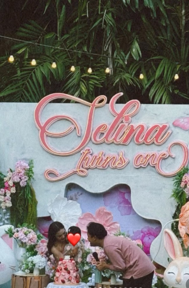 Digelar outdoor, dekorasi acara tampak bernuansa pink dengan dihiasi beragam bunga bernuansa senada serta tulisan Selina Turns One. Kue ulang tahun Selina juga didesain dengan warna pink yang tersusun dari 2 tingkat. Foto: Instagram/@mykylinz_