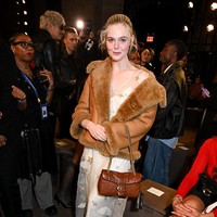 Slip dress berpadu jaket sterling menjadi andalan Elle Fanning saat duduk di front row Coach. Tidak ketinggalan, tas ikonis Tabby Bag dari brand asal Amerika Serikat ini. (Foto: Gilbert Flores/WWD via Getty Images)