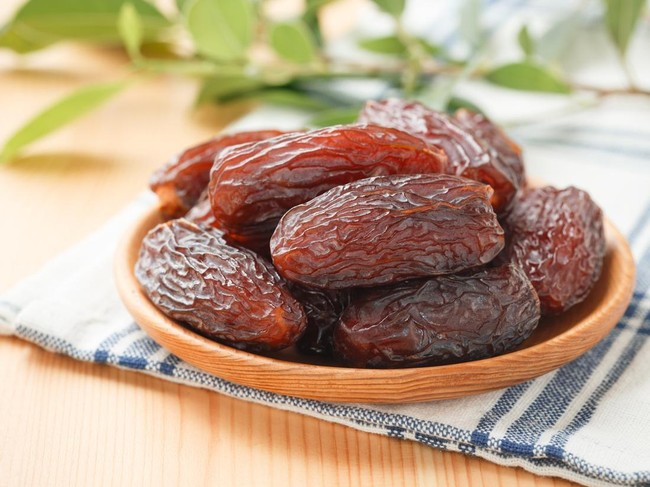 Date fruit in wood bowl on placemat, Dried date palm fruits top view