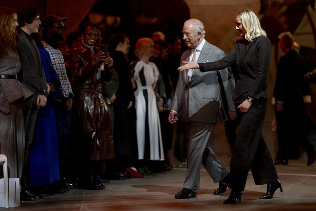 Bergaya necis dalam balutan setelan abu-abu lengkap dengan pocket square, ia berjalan menuju area catwalk sambil menyapa tamu undangan sebelum duduk di front row bersama desainer Stella McCartney dan Sean McGirr dari Alexander McQueen. Di dalam venue, ayah Pangeran William dan Harry itu didampingi oleh CEO British Fashion Council Laura Weir. (Foto: Aaron Chown/PA Images via Getty Images)