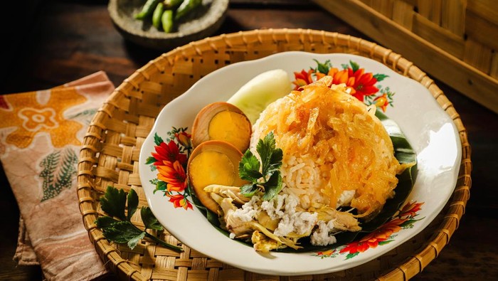 Nasi Liwet Solo, the signature rice dish from Solo / Surakarta. It consists of savoury steamed rice, white chicken curry, soy-braised egg, and spicy chayote squash curry. The dish is plated on a modest crockery and underlined with woven bamboo tray.