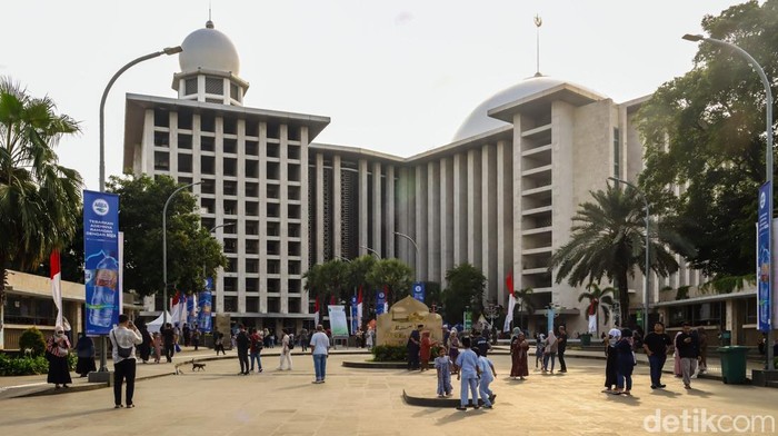 Warga berfoto di depan papan nama Masjid Istiqlal, Jakarta, menjelang berbuka puasa. Area ini menjadi spot favorit keluarga untuk mengabadikan momen Ramadan.