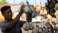 Pedagang musiman mengupas kelapa muda bakar di tepi pantai Desa Peunaga Rayeuk, Kecamatan Meureubo, Aceh Barat, Aceh, Sabtu (21/2/2026). ANTARA FOTO/SYIFA YULINNAS