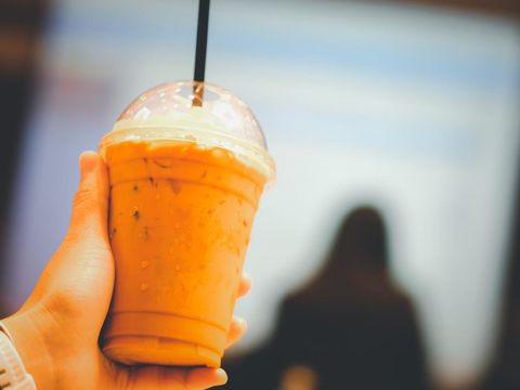 Hand holding a glass of cold Thai milk tea in meeting room