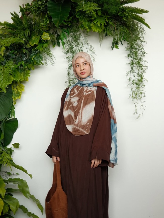 Natasha Rizki membentuk hijab pashmina viscose bermotif abstrak nuansa biru-cokelat dengan long dress berwarna cokelat tua memberikan tampilan syari dan elegan. Penggunaan material kain yang ringan dengan juntaian hijab yang menjuntai rapi menutupi dada, cocok menjadi inspirasi busana yang nyaman dan santun untuk menghadiri acara buka puasa bersama. Foto: Dok. Instagram @leu__official.