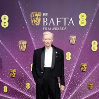 Salah satu tampilan paling mencuri perhatian datang dari Tilda Swinton. Alih-alih mengenakan gaun, ia memilih setelan jas dari Chanel. Jaket tuksedo cropped, celana high-waisted, serta bahu tegas menciptakan proporsi yang kuat dan androgini, sekaligus menjadi pernyataan gaya berbeda di antara dominasi gaun malam. (Foto: Aurore Marechal/BAFTA/Getty Images for BAFTA)