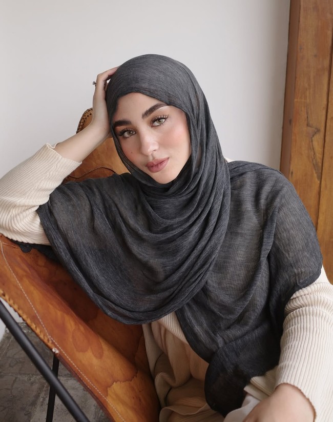 Margin Wieheerm tampil memukau dengan perpaduan pashmina crinkle viscose polos hitam yang disampirkan ke depan, menciptakan siluet wajah yang tegas namun tetap terlihat lembut. Foto: Dok. Instagram @marginw.