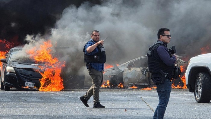 Firefighters work to extinguish flames at a convenience store set on fire by members of organized crime following a military operation in which a government source said Mexican drug lord Nemesio Oseguera, commonly known as El Mencho, was killed, in Zapopan, Mexico, February 22, 2026. REUTERS/Gilberto Gallo