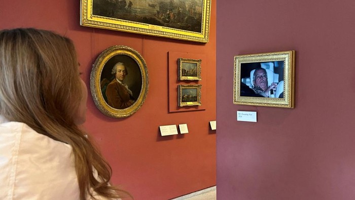 A person looks at a framed picture of Andrew Mountbatten Windsor, younger brother of Britains King Charles, formerly known as Prince Andrew, hung by activists from anti-billionaire campaign group Everyone Hates Elon in the Louvre museum, in Paris, F