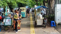 Lapak-lapak semi permanen berjajar di atas ruang pejalan kaki, mulai dari pedagang makanan hingga minuman.