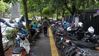 Selain mempersempit ruang berjalan, aktivitas jual beli dan parkir sepeda motor di atas trotoar turut menimbulkan penumpukan sampah.