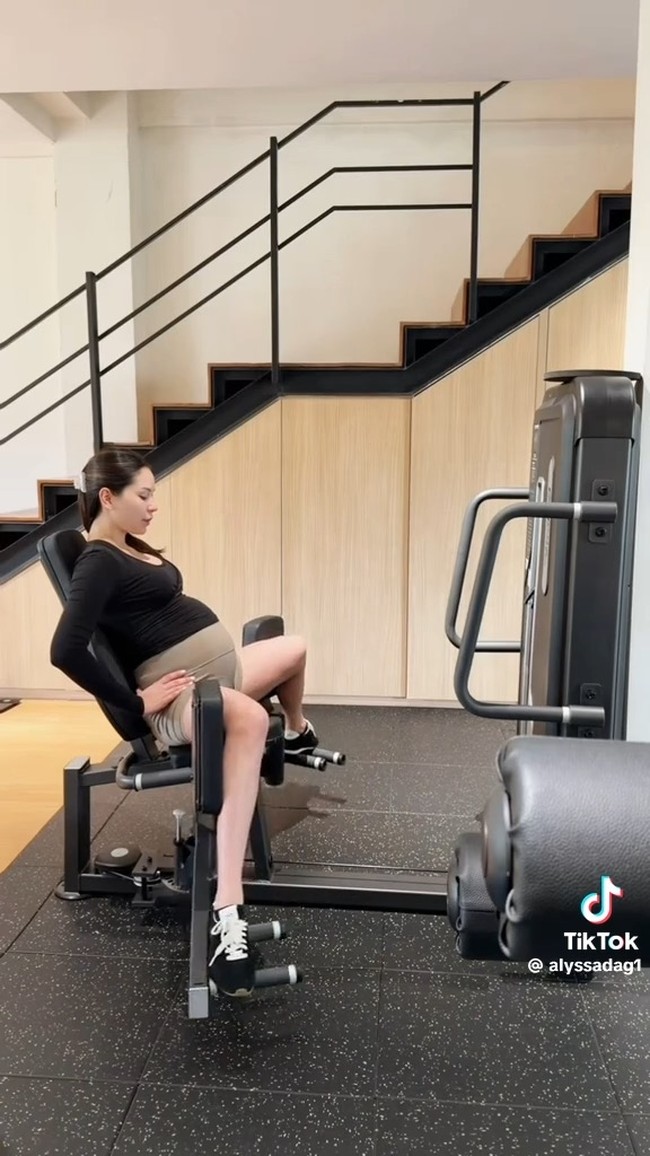 Alyssa juga memanfaatkan mesin leg exercise sambil duduk. Gerakan ini membantu memperkuat otot paha dengan posisi yang lebih stabil dan aman bagi ibu hamil. Foto: TikTok/@alyssadag1