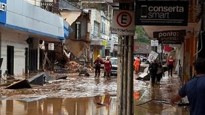 Handout picture released by the Minas Gerais Fire Department showing firemen working on a flooded street caused by heavy rains in Juiz de Fora, Minas Gerais state, Brazil on February 24, 2026. At least 20 people died, dozens are missing and more than