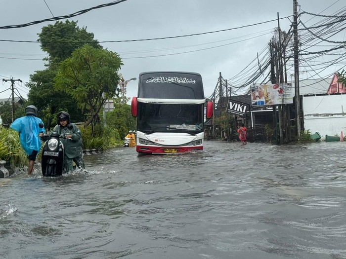 Bus besar melaju di tengah genangan banjir di Jalan Bypass Ngurah Rai, Denpasar, Selasa (24/2/2025). (I Nyoman Adhisthaya Sawitra/detikBali)