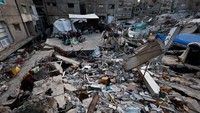Keluarga Palestina Abu Naji berkumpul di antara reruntuhan rumah mereka yang hancur akibat ofensif Israel selama dua tahun terakhir di Gaza City (23/2/2026). REUTERS/Mahmoud Issa
