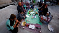 Usai berdoa, keluarga itu menyantap hidangan iftar secara sederhana. Makanan berbuka disajikan di atas alas seadanya di antara reruntuhan. REUTERS/Mahmoud Issa