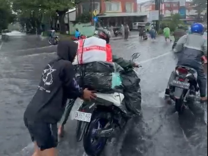Sejumlah pengendara mendorong motor di tengah genangan banjir Jalan Bypass Ngurah Rai, Denpasar, Selasa (24/2/2026). (I Nyoman Adhisthaya Sawitra/detikBali)